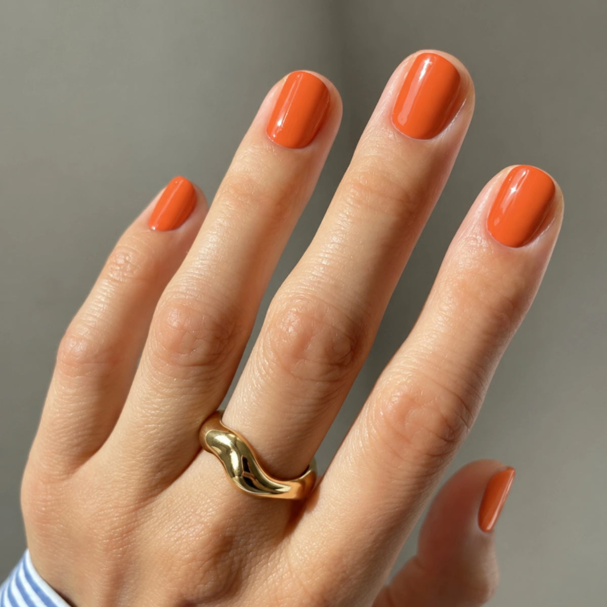 Hell orangene Naegel mit orangenen UV-Nagelfolien gemacht, Handbild Nahaufnahme von hell orangenen Naegeln.